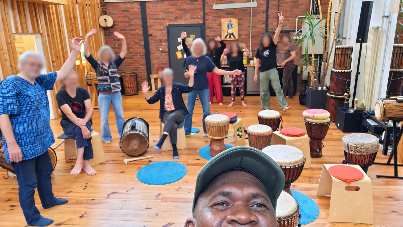 Über mich Billy Konaté mit Teilnehmenden und Djembes nach einem Trommelworkshop