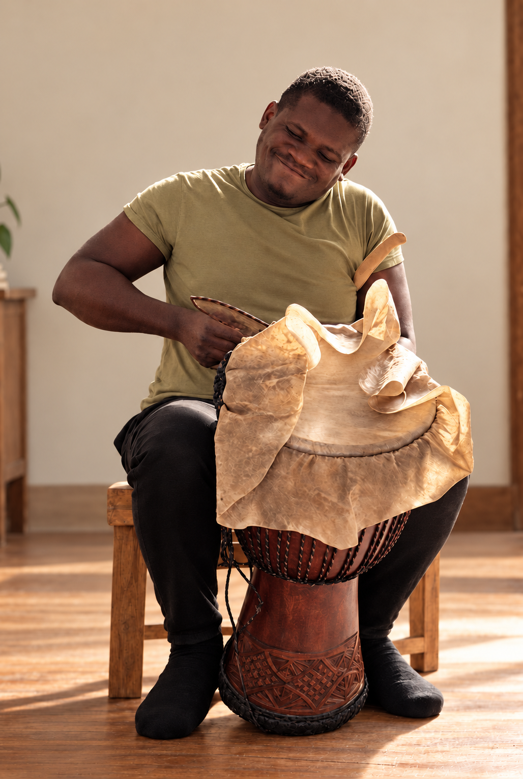 Instrumente Billy Konaté spannt und richtet eine Djembe aus