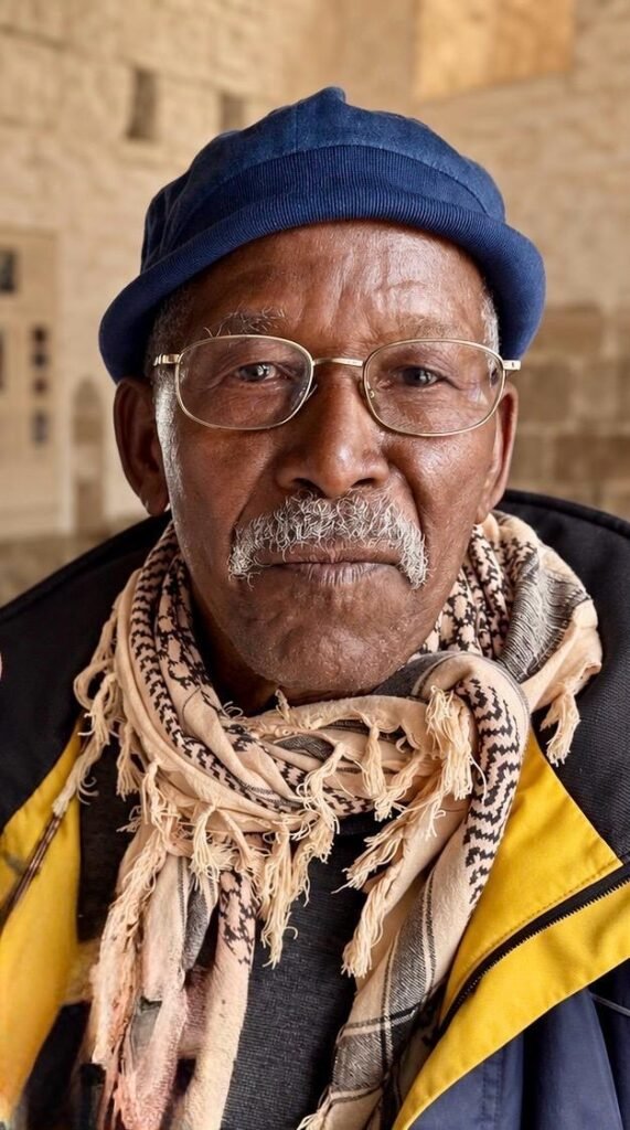 Porträt von Famoudou Konaté mit blauer Mütze, Brille und Schal