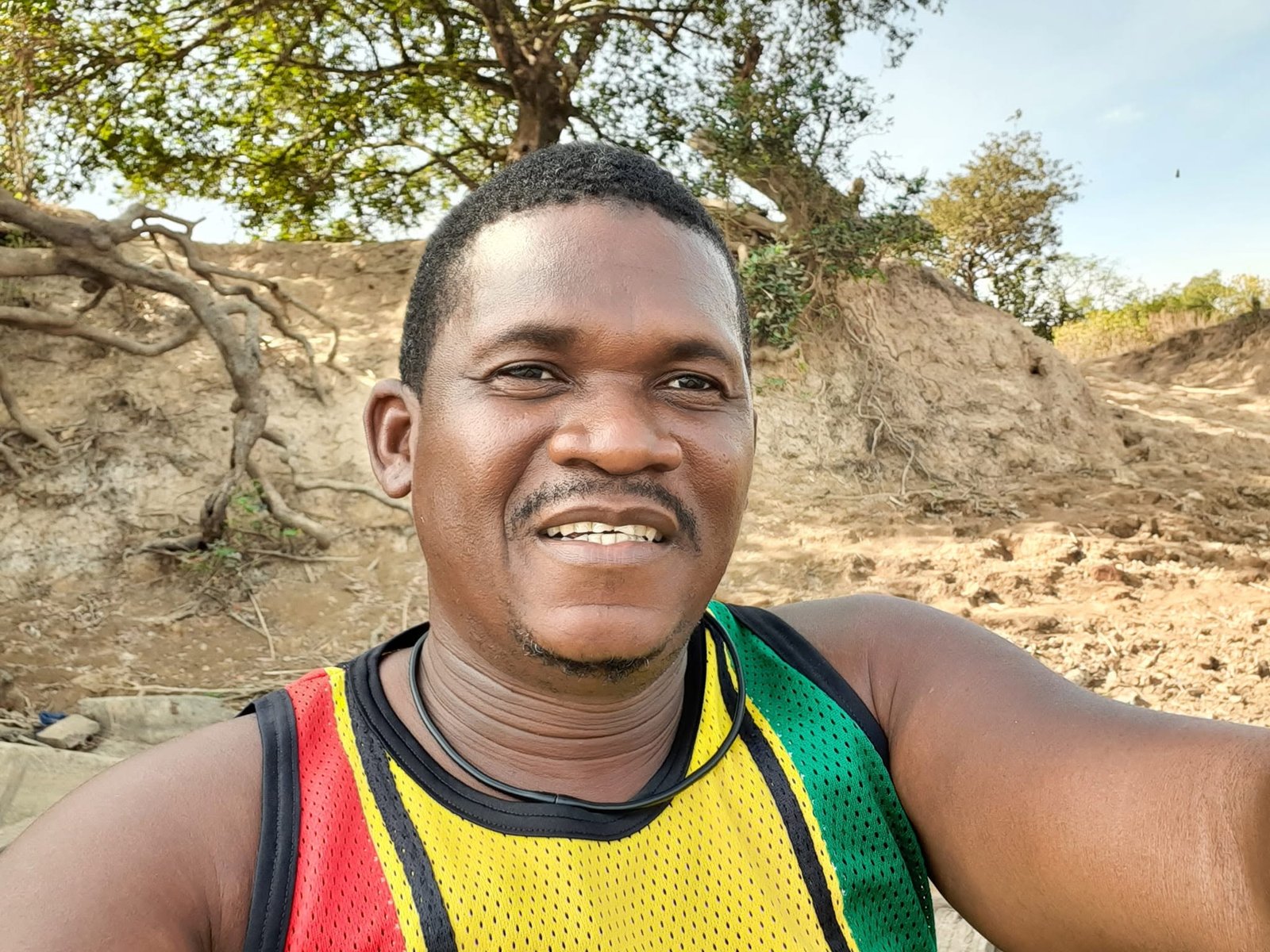 Billy Konaté lächelt unter einem Baum in Guinea