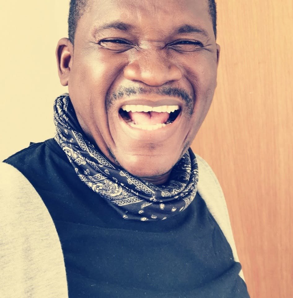 Billy Konaté lacht in die Kamera und trägt ein gemustertes Halstuch